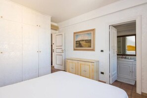 A bedroom with a bed, a wardrobe, a radiator, and a bathroom visible through an open door.