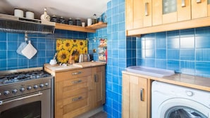 Una cocina con azulejos azules, armarios de madera, una estufa y una lavadora.