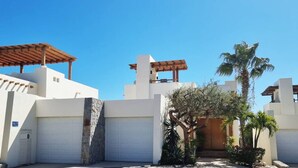 Un edificio moderno con pareti bianche, una parete in pietra e un pergolato in legno.