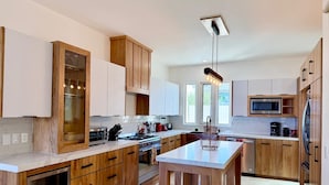 Una cucina moderna con mobili in legno, un'isola centrale, elettrodomestici in acciaio inossidabile e un'ampia finestra che garantisce luce naturale.