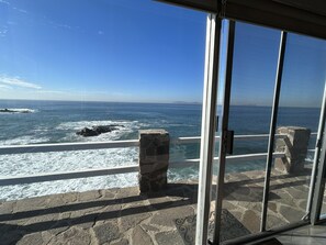 A coastal view from a balcony with stone pillars, a glass railing, and a clear blue sky. -  Oceanfront, Beautiful view, Romantic, Extra large, Relaxing, Near to Golfing. (Punta Bandera)