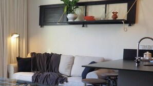 A cozy living area with a sofa, a coffee table, and a small kitchen area with a counter and stools. - Cistellaire, with access to indoor swimming pool (Olot)