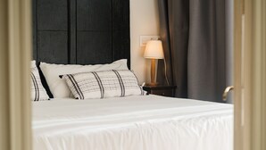 A neatly made bed with white bedding and patterned pillows, a bedside lamp, and a dark wooden headboard. - Cistellaire, with access to indoor swimming pool (Olot)