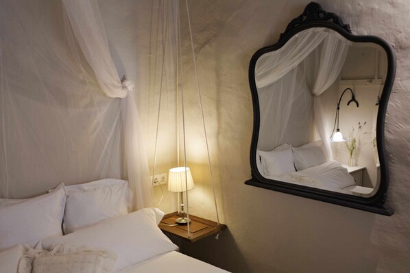 A bedroom with a canopy bed, a bedside lamp, and a mirror on the wall.