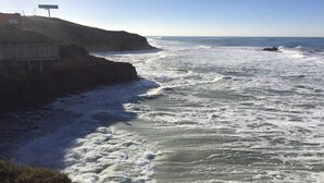 A coastal scene with waves crashing onto a rocky shore.