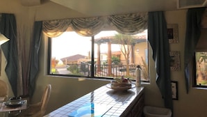 A room with a dining table, chairs, a window with curtains, and a view of the outside. - Newly Re-decorated, 4 Recliner's Oceana, On the beach front, downtown Rosarito. (Centro Playas)