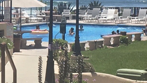 A pool area with lounge chairs and umbrellas, a lamp post, and a view of the ocean. - Newly Re-decorated, 4 Recliner's Oceana, On the beach front, downtown Rosarito. (Centro Playas)