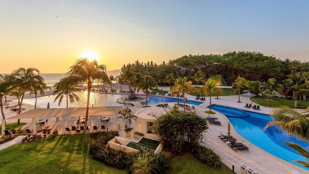 A resort pool area with multiple swimming pools, lounge chairs, and palm trees. - Villa Magna 1 Bedroom Tower 3 on 2nd Floor Oceanfront Sleep up to 4 (Nuevo Nayarit)