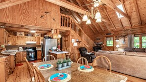 Eine geräumige Holzhütte mit Essbereich, Küche und Wohnzimmer.