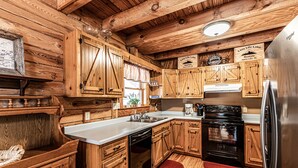 Eine rustikale Kücheneinrichtung im Blockhausstil mit Holzschränken, einem Edelstahlkühlschrank und einem Geschirrspüler.