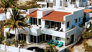 Une maison moderne à deux étages, dotée d’une piscine, d’un espace de détente extérieur et offrant une vue sur le paysage environnant.