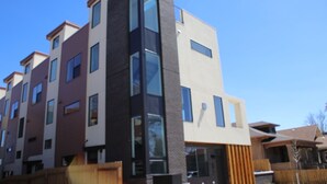 Ein mehrstöckiges Wohngebäude mit moderner Architektur, große Fenster und eine Fassade aus Backstein und Glas.