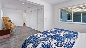 Un dormitorio con cama, ventana con persianas, una silla y armario.