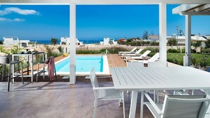 A poolside area with a view of the sea, a pool, and outdoor seating. - Marza Residence – Bruna - Private villa with pool (Reitani)