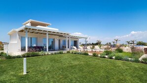 A modern house with a covered patio, a well-maintained lawn, and a view of the sea. - Marza Residence – Bruna - Private villa with pool (Reitani)