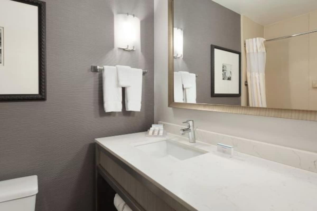 A modern bathroom with a white sink, a mirror, and a towel rack.