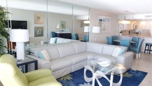 A modern living room with a sectional sofa, a glass coffee table, and a yellow armchair.