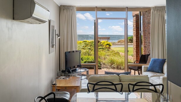 Une chambre moderne dotée d’une grande porte-fenêtre coulissante donnant sur un balcon avec vue sur la mer.
