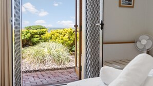 Une chambre avec un lit, un ventilateur et une vue sur un jardin et la mer.