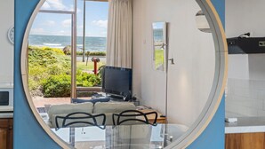 Une chambre moderne dotée d’un grand miroir ovale qui reflète une vue sur l’océan et la végétation environnante.