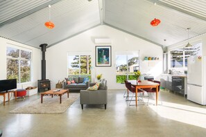 Amplia sala de estar con chimenea, sofá, mesa de comedor y zona de cocina.