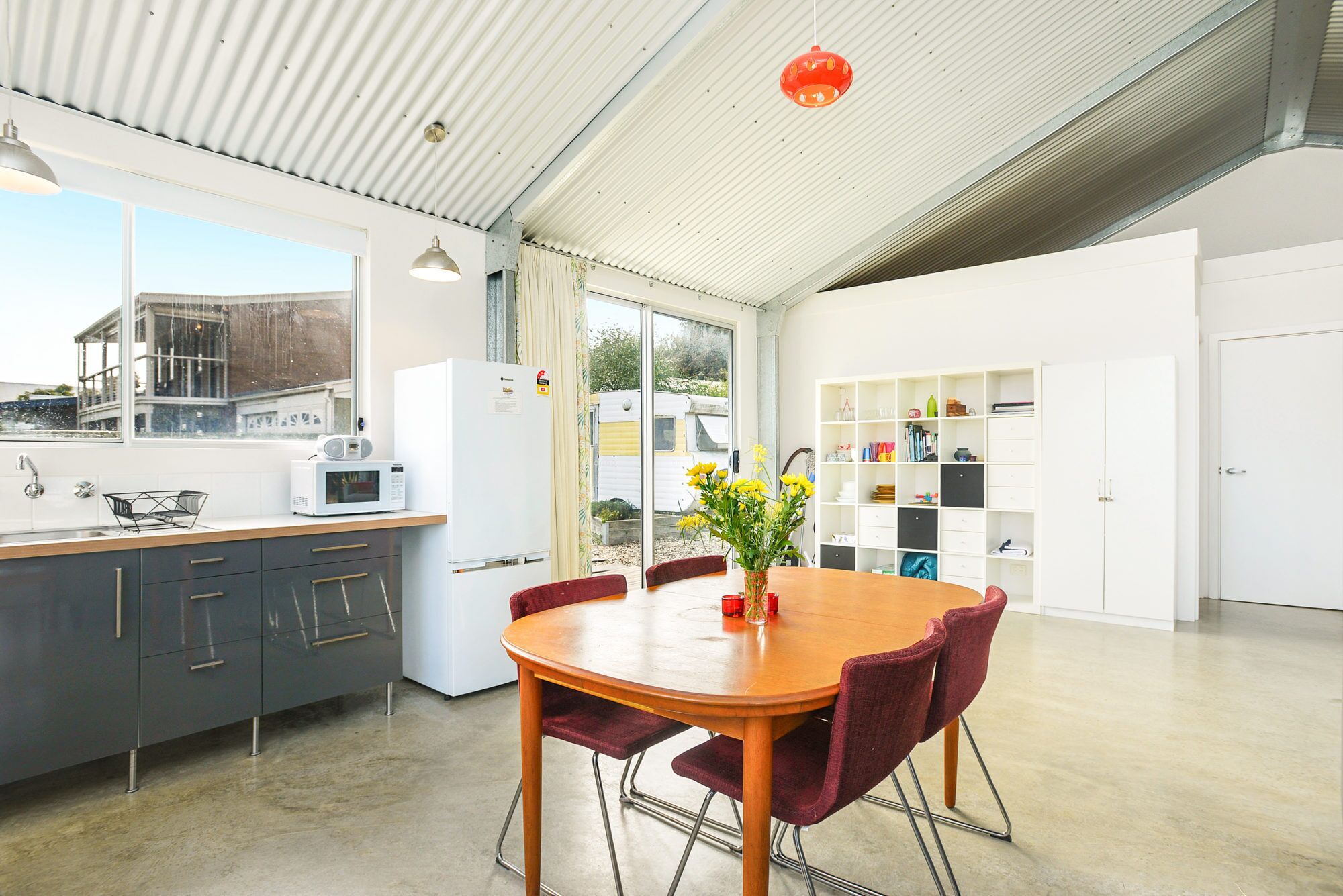 Une cuisine moderne avec un coin repas, comprenant une grande fenêtre, un réfrigérateur, un four à micro-ondes et une table à manger avec des chaises.