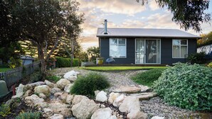 Una casa moderna con un camino de piedra que conduce a la entrada, rodeada de vegetación y un patio cercado.
