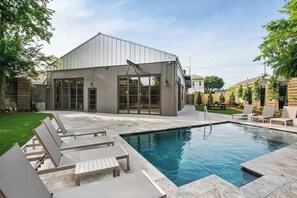 Une maison moderne dotée d’une piscine, d’un espace extérieur aménagé et d’une pelouse bien entretenue.