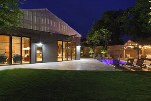 Een modern huis met een zwembad, buitenzitplaatsen en een goed verlicht terras.