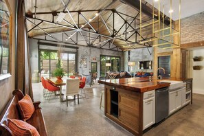 Une cuisine spacieuse dotée d’un îlot central, d’un éclairage moderne suspendu et d’un plafond au style rustique.