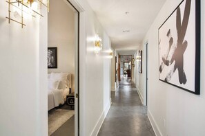 Un couloir d’hôtel avec un lit, une œuvre d’art et un luminaire.