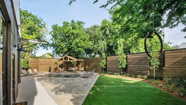 Un jardin avec une piscine, une terrasse en bois et une pelouse verdoyante.