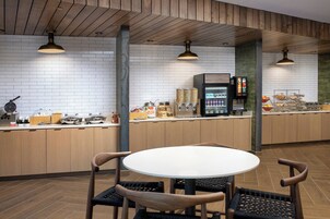 Uma cozinha moderna com uma mesa redonda e cadeiras, uma cafeteira e diversos alimentos sobre o balcão.