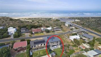 Stunning homes with pools and solar panels, set amidst a scenic beachside location.