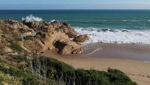 Costa rocosa con una playa arenosa y un saliente rocoso.