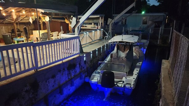 A boat docked at a pier with a blue-lit water feature in the foreground. - Key largo waterfront jewel (Key Largo)