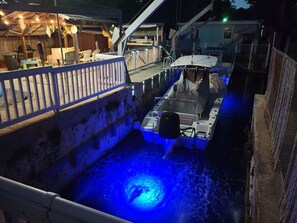 A boat docked at a pier with a blue-lit water feature in the foreground. - Key largo waterfront jewel (Key Largo)