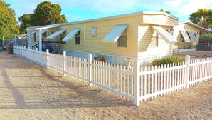 A mobile home with a white picket fence, a covered porch, and a small garden area. - Key largo waterfront jewel (Key Largo)