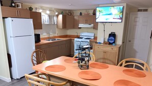 A compact kitchen with wooden cabinets, a white refrigerator, a stove, and a TV mounted on the wall. - Key largo waterfront jewel (Key Largo)