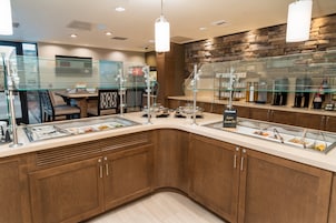 A modern breakfast bar with glass partitions, a stone wall, and a variety of food items.