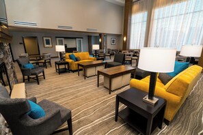 A hotel lobby with seating arrangements, a fireplace, and a large window with curtains. - Staybridge Suites Coeur d'Alene by IHG (Coeur d'Alene)