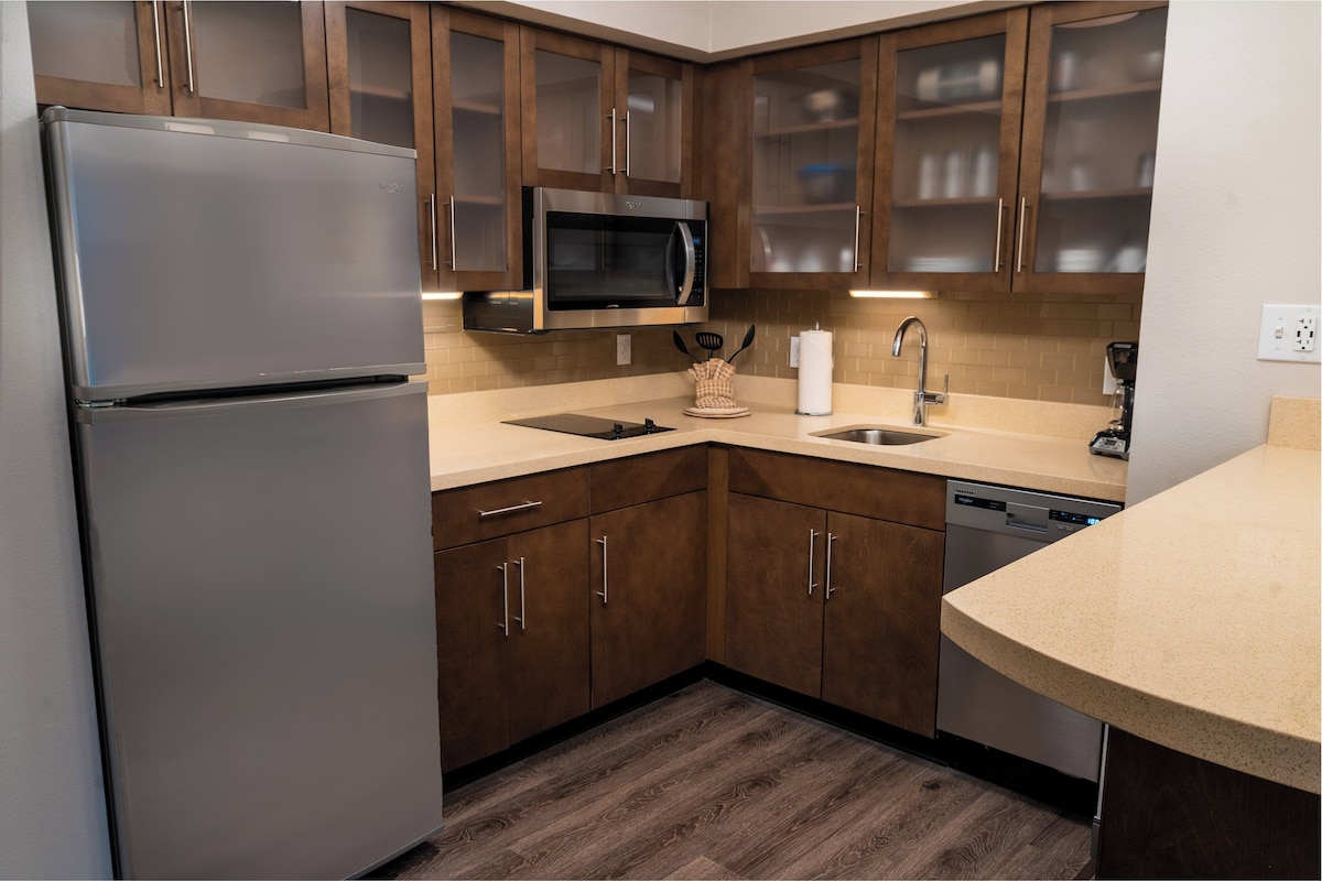 A modern kitchen with stainless steel appliances, wooden cabinets, and a dishwasher.