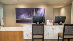 Una mesa de recepción con dos monitores, una encimera de mármol y un cuadro grande con una imagen de un puente.