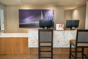 A reception desk with two monitors, a marble counter, and a large framed picture of a bridge.