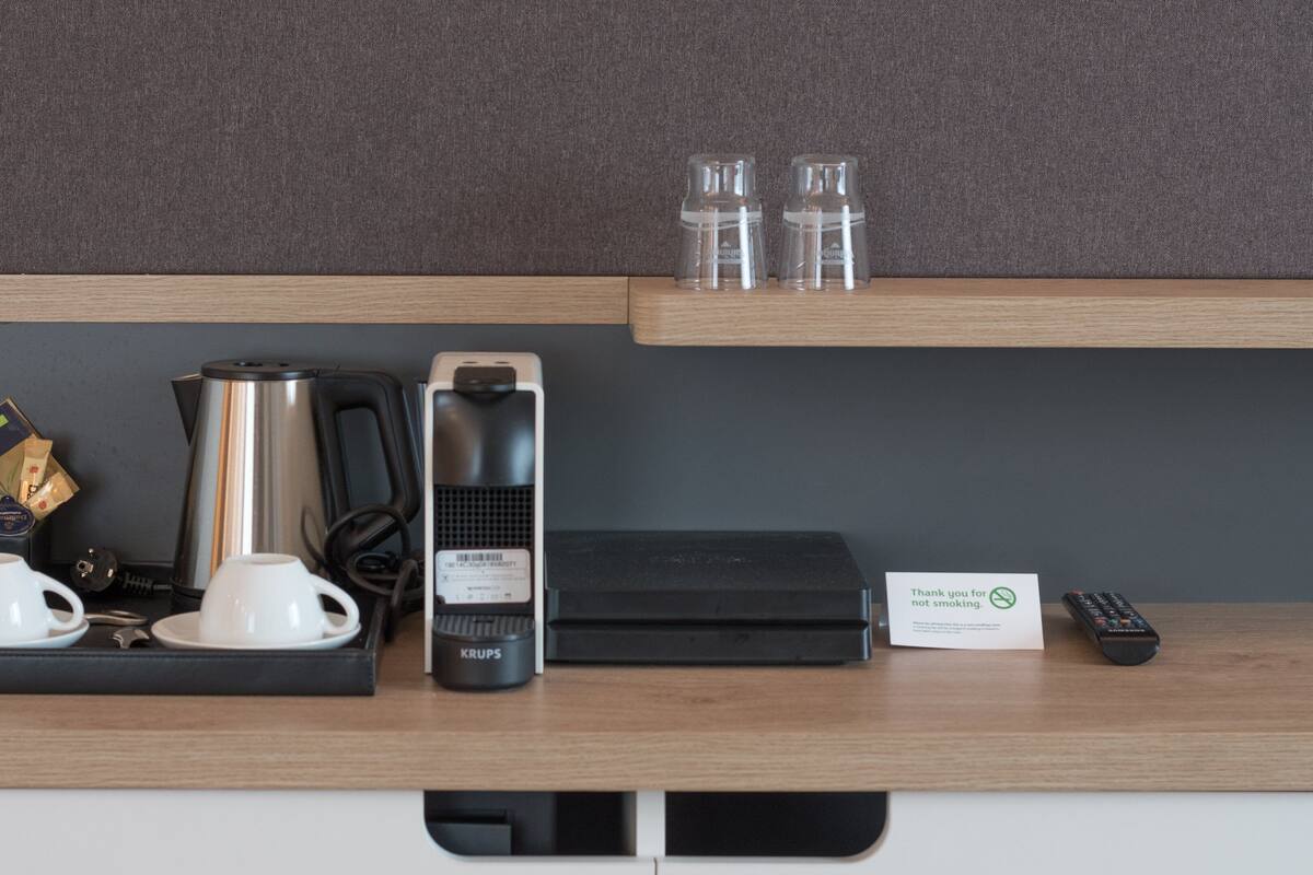 A hotel room's minibar with a coffee maker, tea kettle, and tea packets.