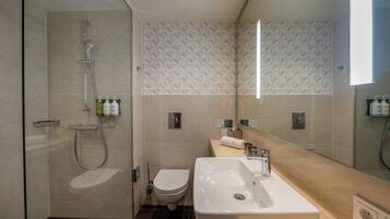 A modern bathroom with a glass shower enclosure, a toilet, a sink, and a mirror.
