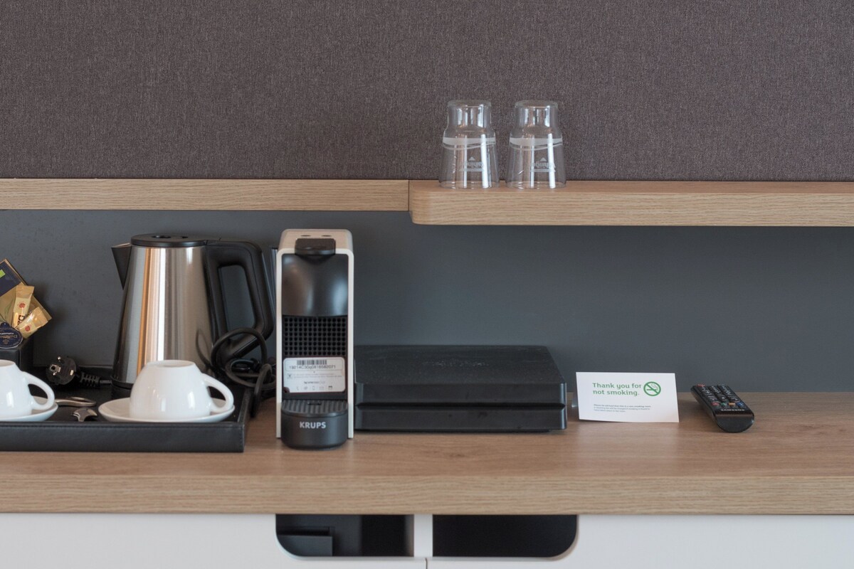 A hotel room's minibar with a coffee maker, tea kettle, and tea packets.