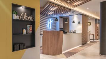 A reception area with a modern design, featuring a wooden reception desk, a black shelf with decorative items, and a neon sign.