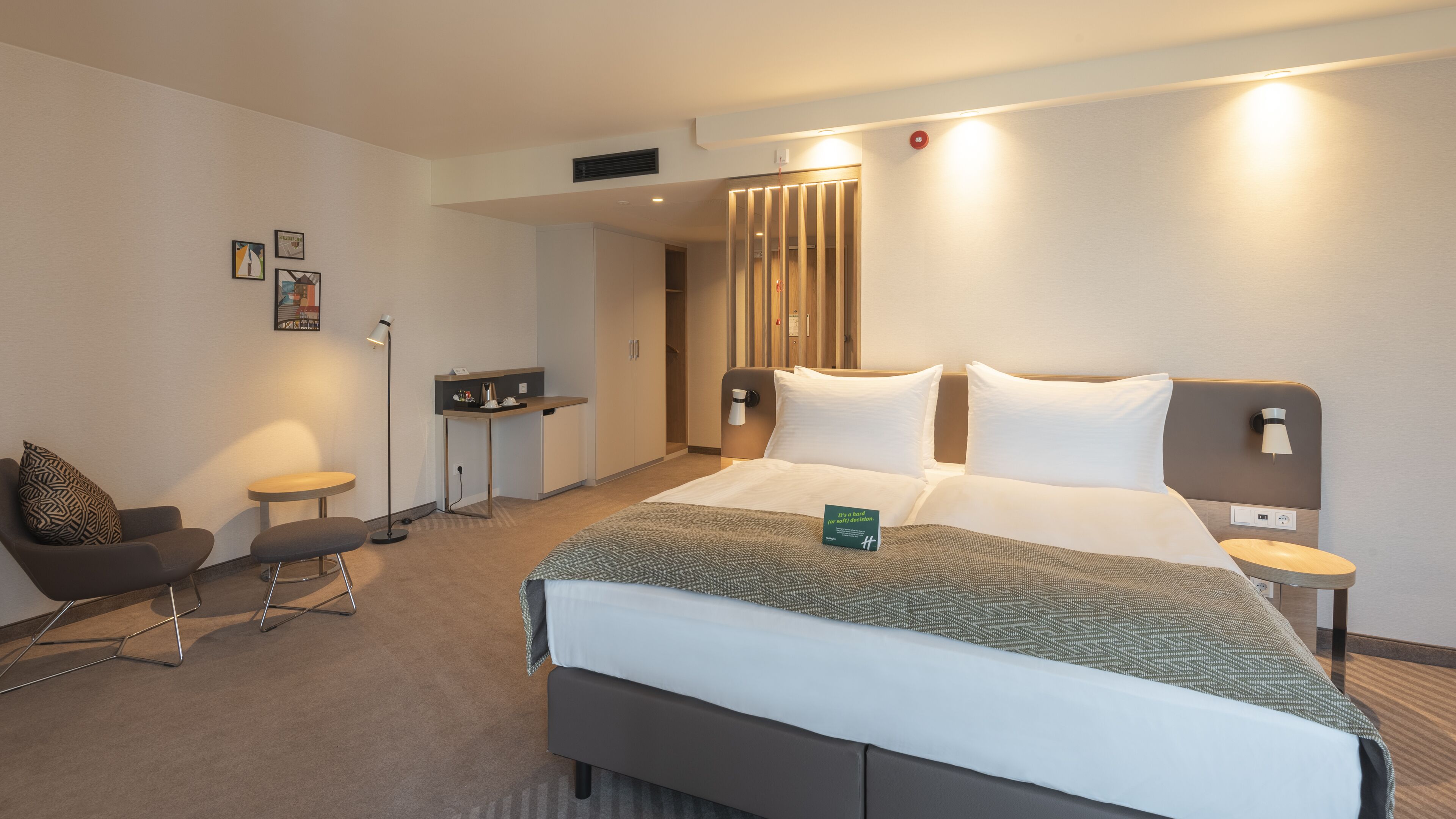A modern hotel room with a large bed, bedside tables, a desk, and a chair.