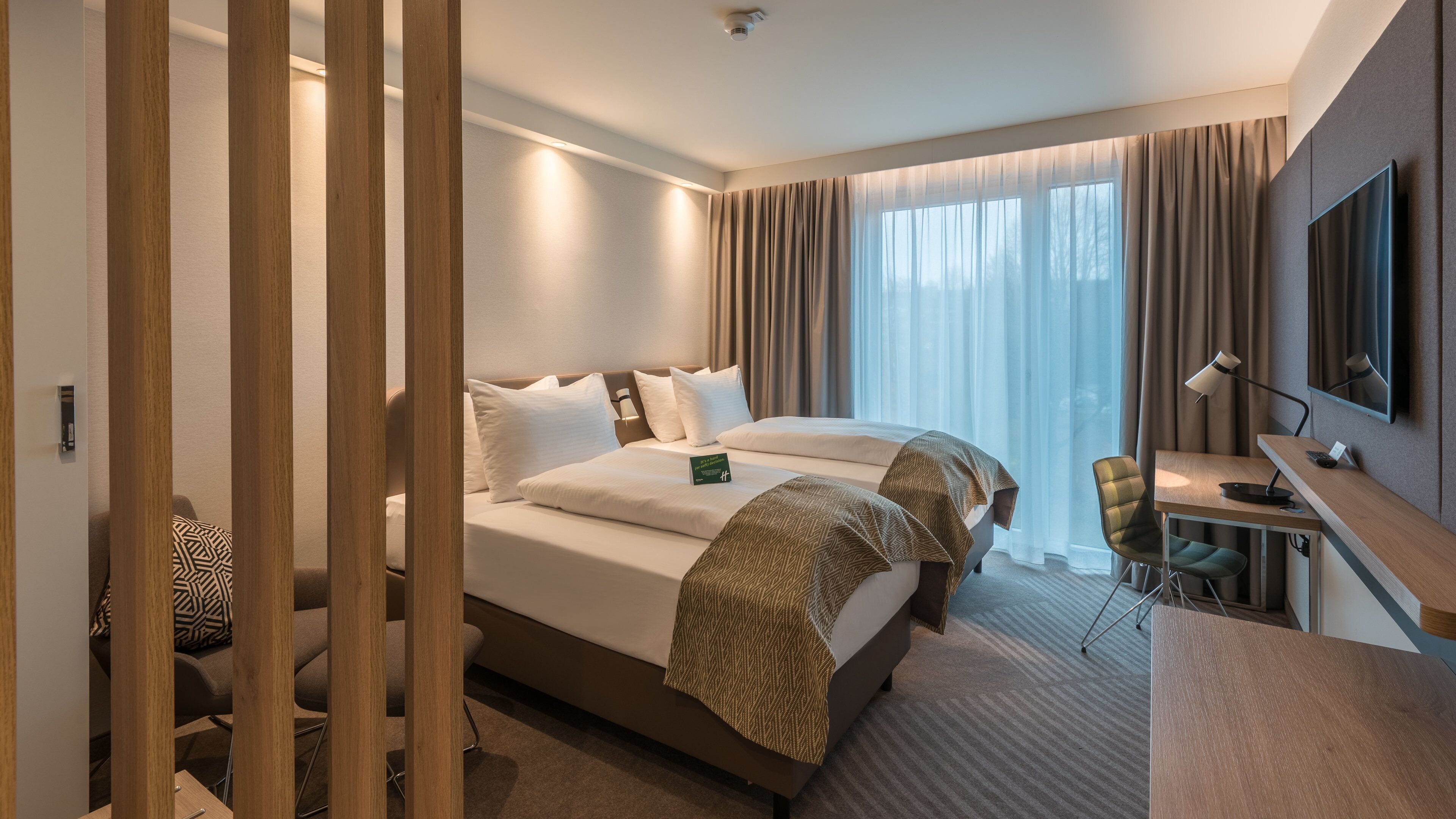 Une chambre d’hôtel avec un lit, un bureau, une chaise et un téléviseur.